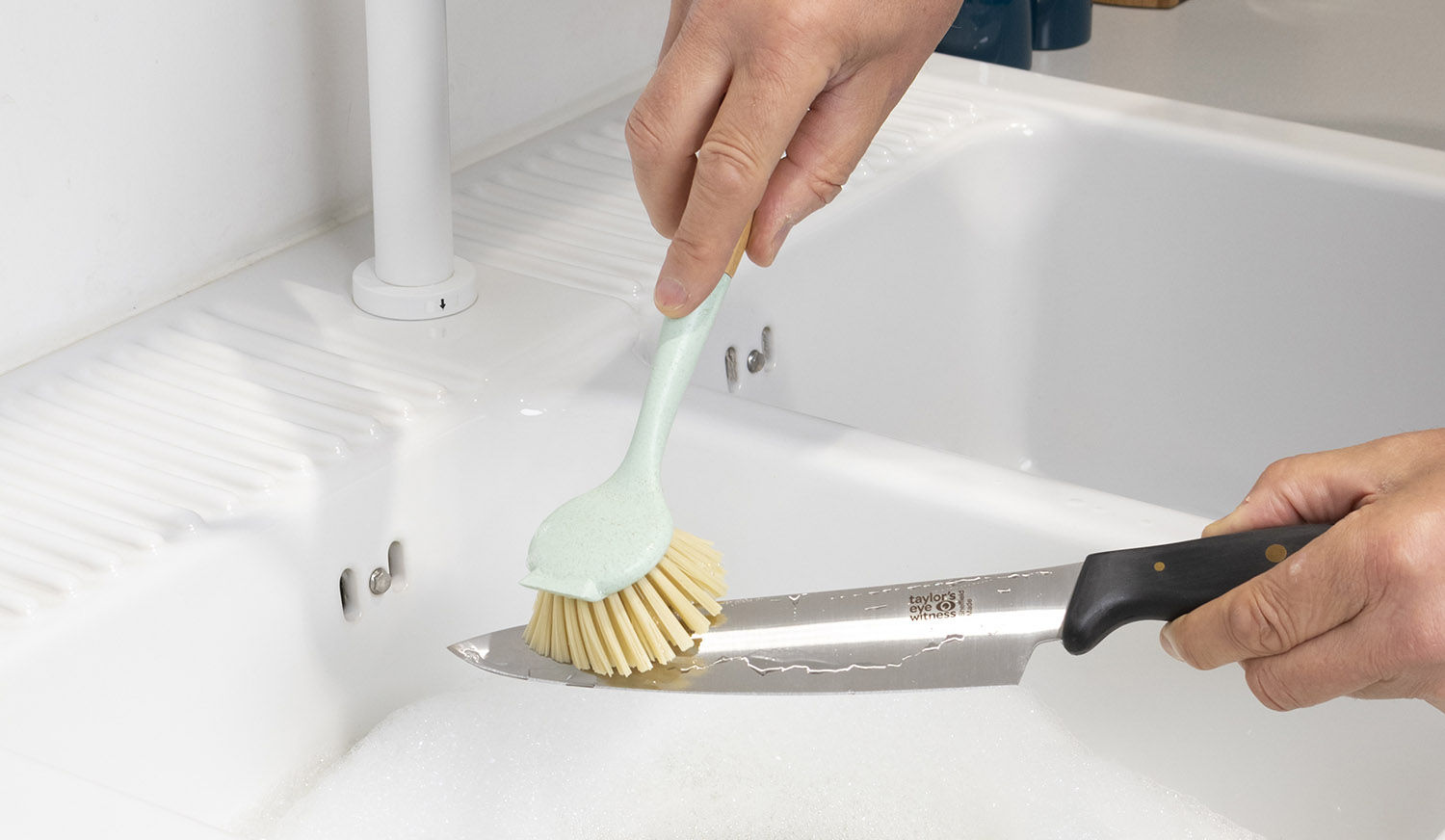 Washing a knife with a dish brush